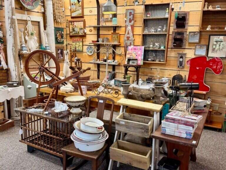 Granny Fay's booth at Twisted Sisters Vintage Market, with an antique spinning wheel, enamelware bowls and farmhouse wall decor