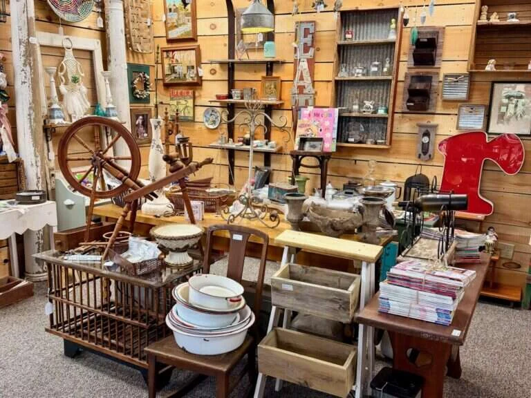 Granny Fay's booth at Twisted Sisters Vintage Market, with an antique spinning wheel, enamelware bowls and farmhouse wall decor