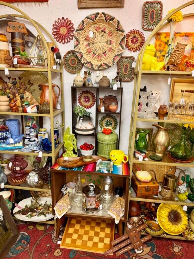 Live Simply Vintage booth at Twisted Sisters Vintage Market, with arched shelves of retro pottery, glassware and woven wall baskets